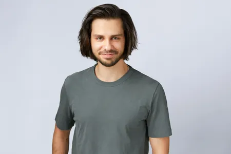 Andrzej, smiling, in a grey t-shirt against a plain backdrop.